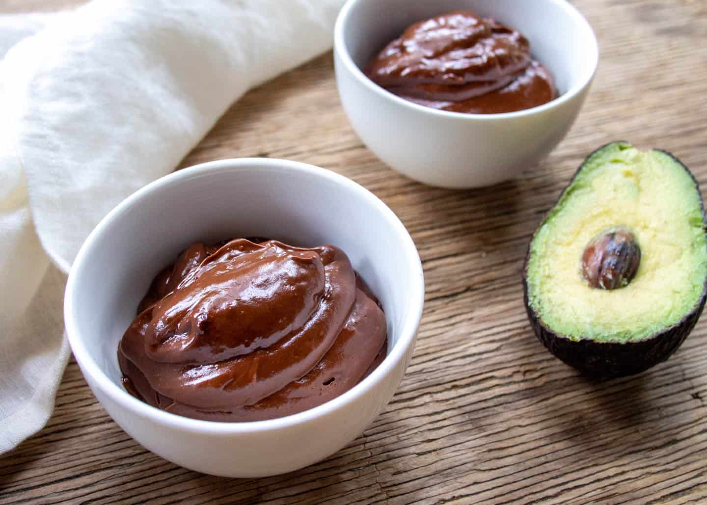 Two bowls avocado pudding with avocado on side