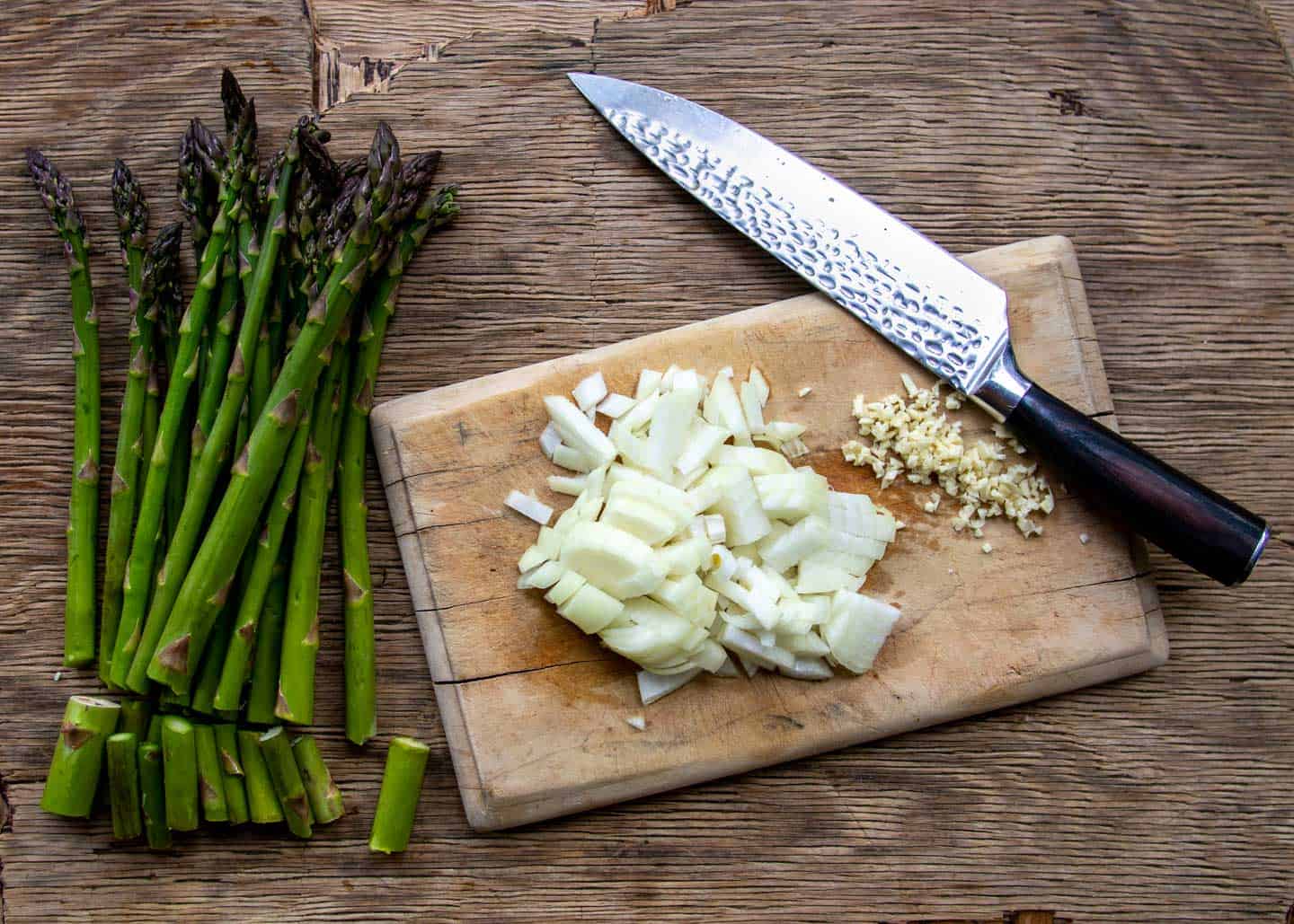 Chopped onion and asparagus on cutting board