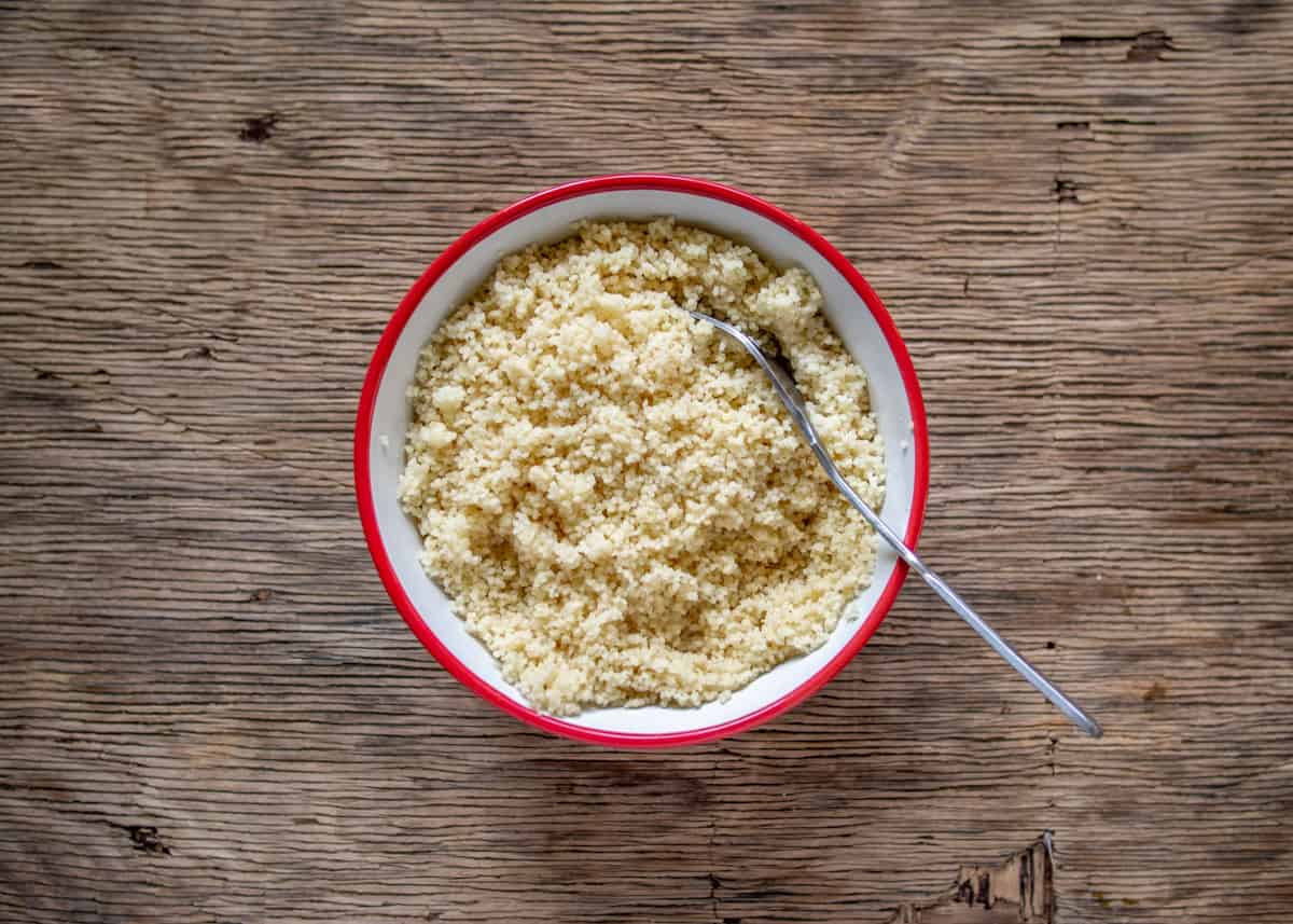 Cooked couscous in bowl fluffed with a fork
