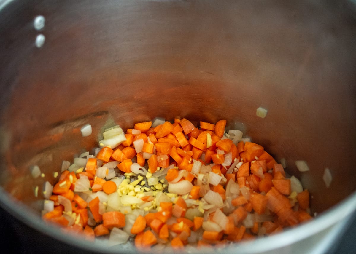 Onion, carrot, garlic, ginger and spices cooking in large pot