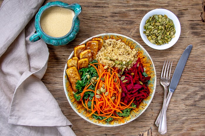 Kale Salad Bowl with Baked Tofu and Glory Bowl Dressing On Wooden Background