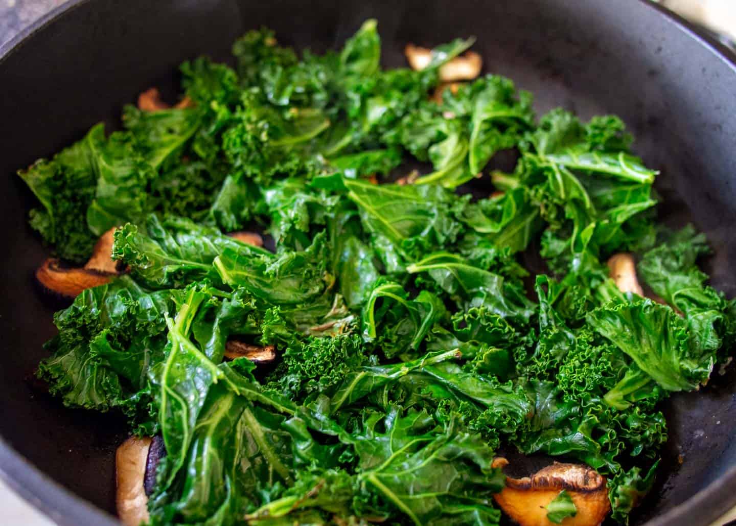 Mushrooms and kale in frying pan