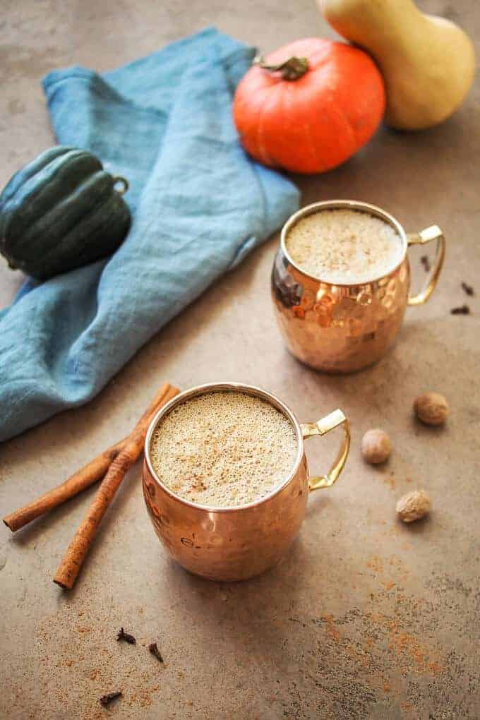 Healthy Pumpkin Spiced Latte in Copper Mugs with Squash and Blue Linen in Background