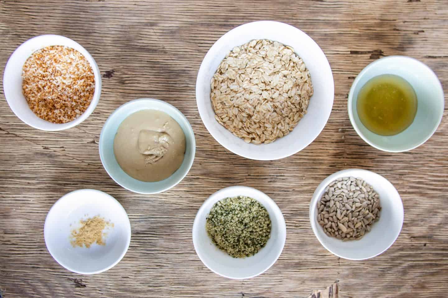 Ingredients in white bowls for no-bake energy balls