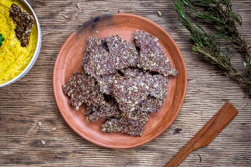 Keto Seed Crackers on Brown Ceramic Plate with Rosemary On Side