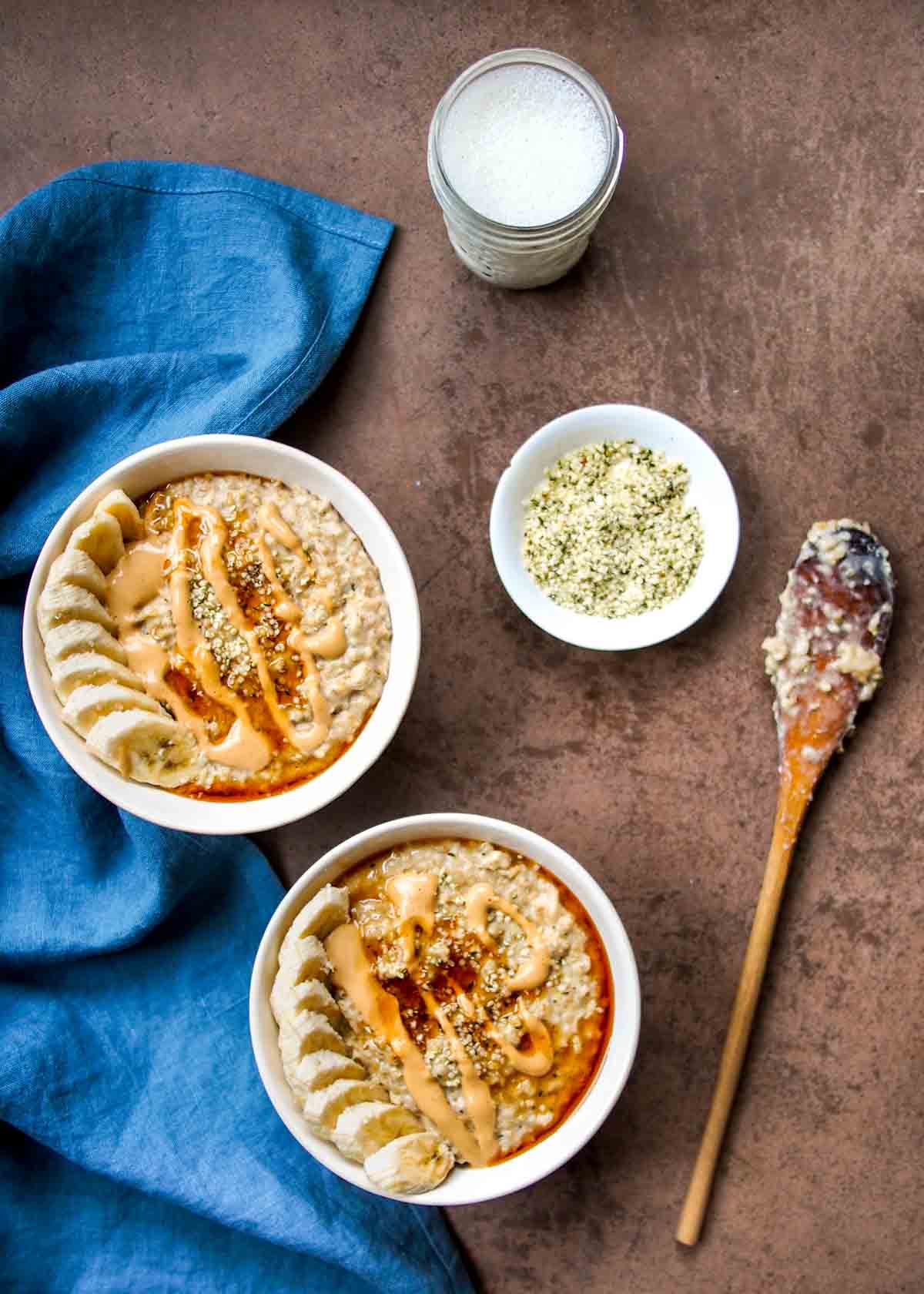 high protein steel-cut oats in white bowls with blue linen napkin and wooden spoon