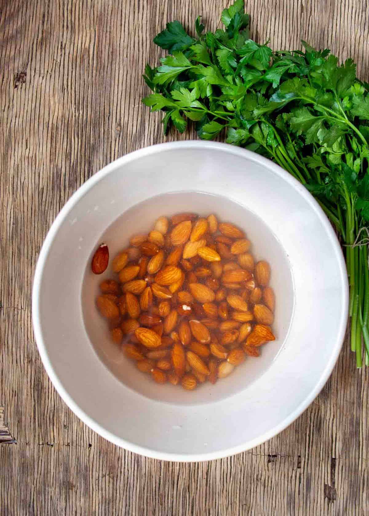 Almonds soaking in white bowl