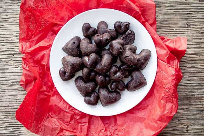 Raw Chocolate Hearts on White Plate with Red Background
