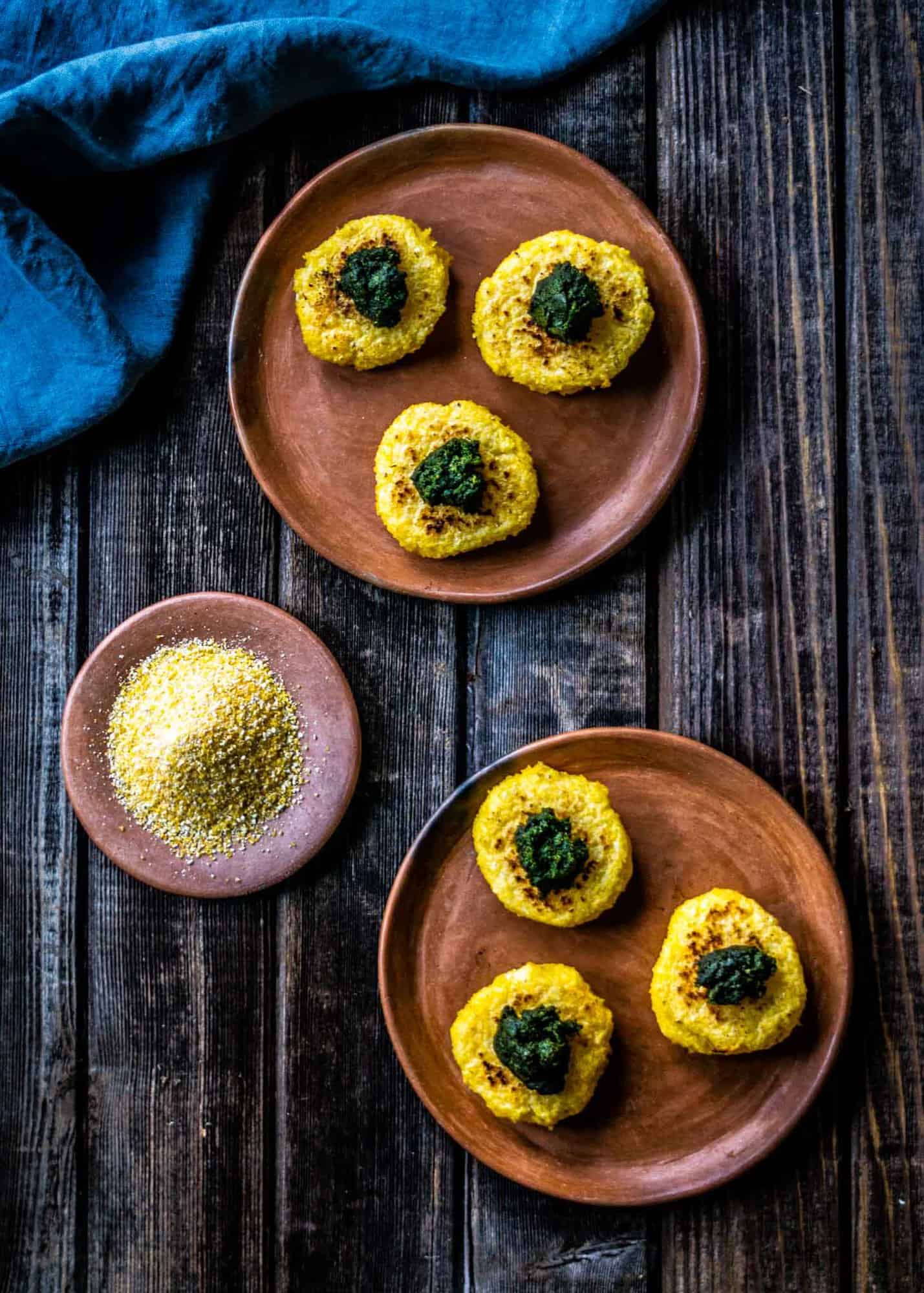 Corn patties topped with pesto on clay plate